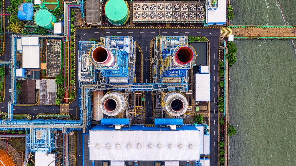 Aerial view of an industrial plant in Jakarta by the waterfront. Features colorful structures and piping.