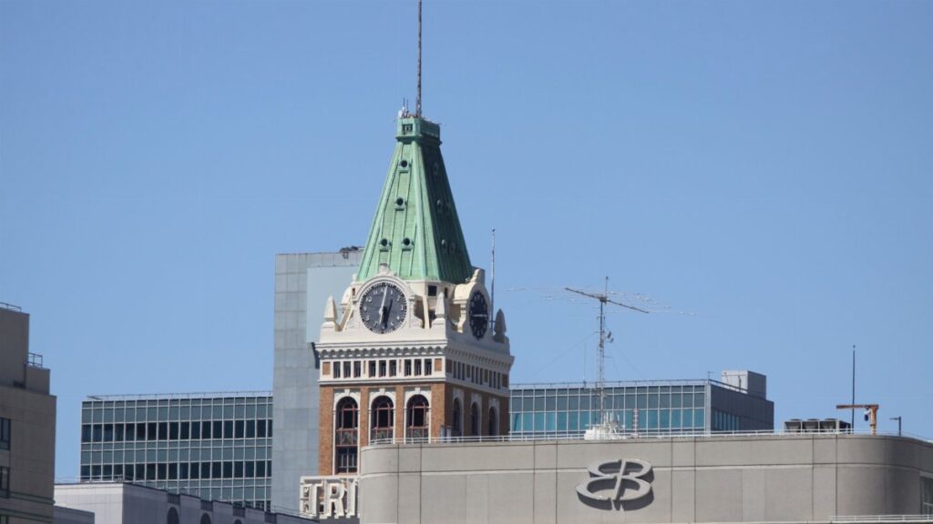 A view of the historic Tribune Tower with its green copper spire and clock face in the Oakland skyline.