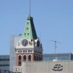 A view of the historic Tribune Tower with its green copper spire and clock face in the Oakland skyline.