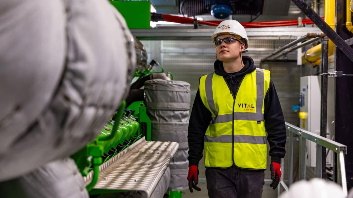 Man in safety gear inspecting factory equipment, ensuring quality control and safety standards.