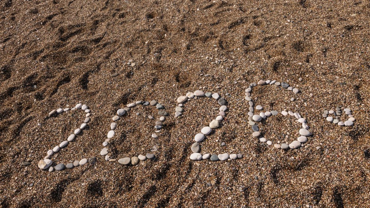 Stones arranged to form the number 2026 on a sandy coastline, creating a natural and creative scene.