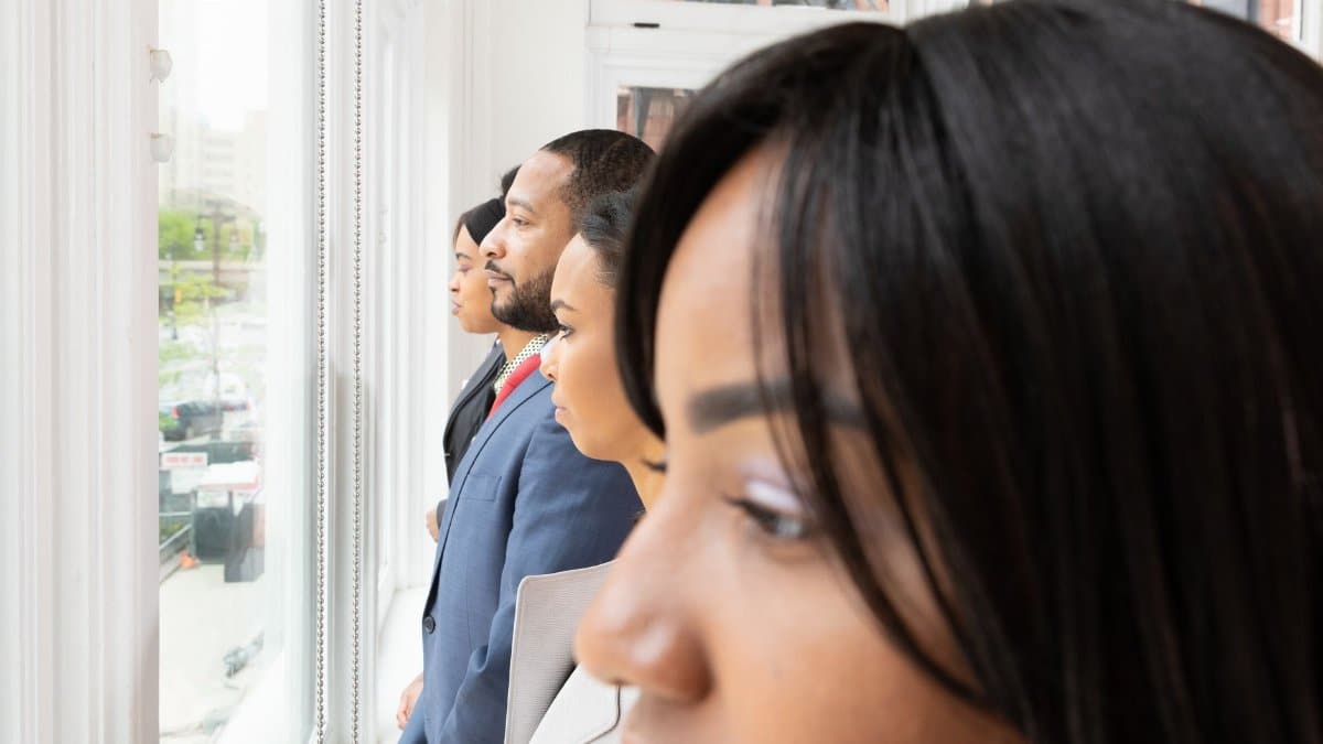A diverse group of business professionals looking thoughtfully out of an office window.