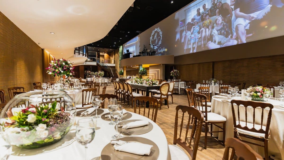 An elegant wedding reception setup with floral arrangements and elegant table settings in a spacious venue.