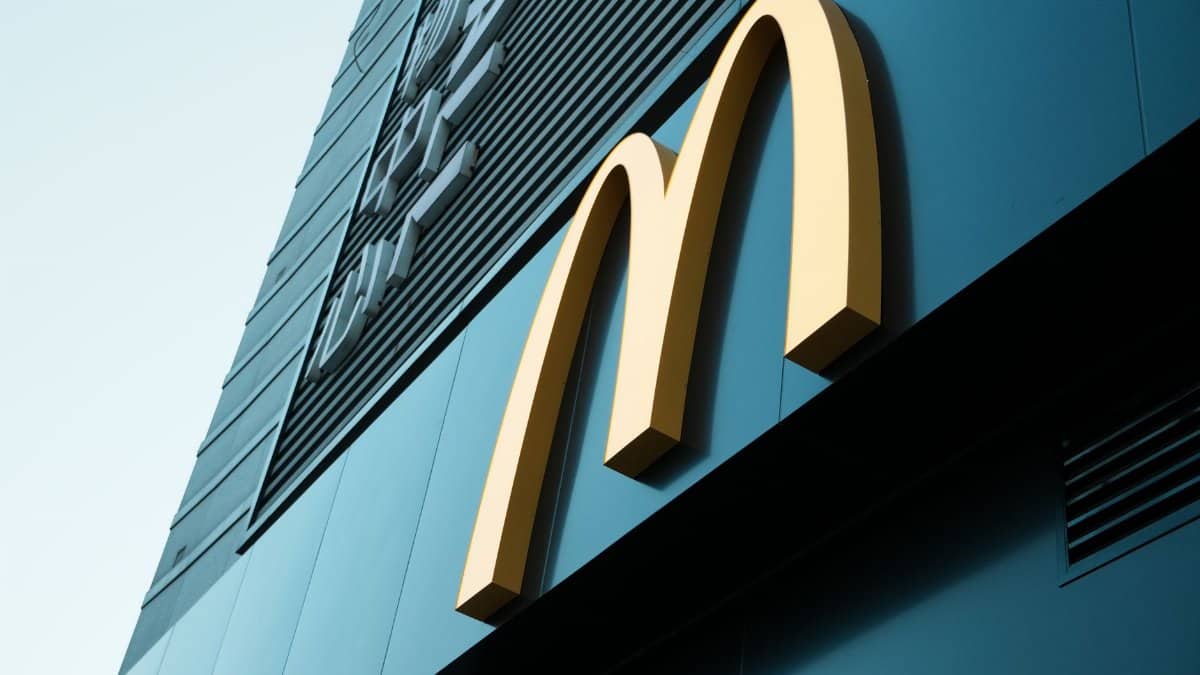 Large fast food restaurant golden arch sign on a modern building facade.