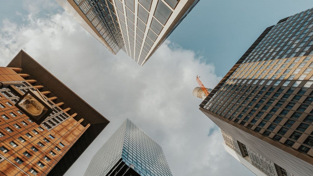 Looking up at diverse modern skyscrapers reaching into a partly cloudy sky.