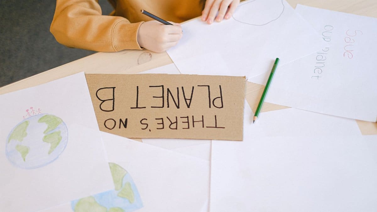 Child engaged in eco-friendly art project with globe drawings and eco messages in a classroom setting.
