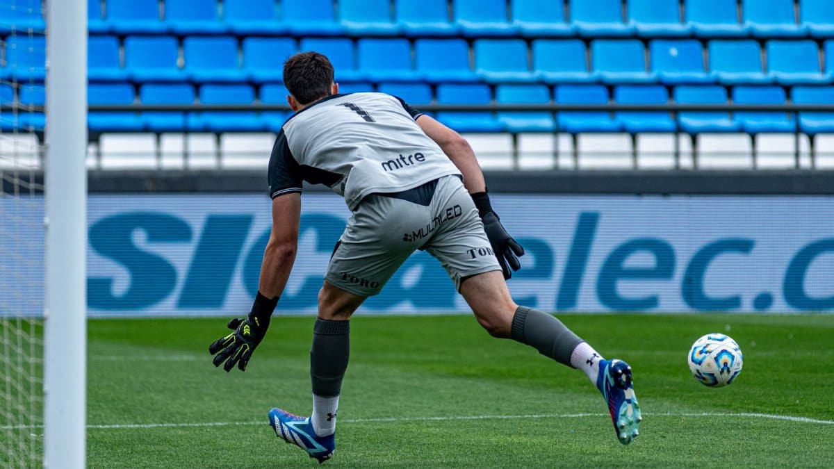 Soccer goalkeeper ready to defend goal during match in outdoor stadium.