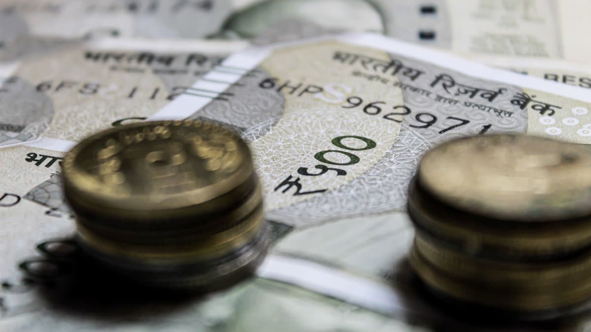 Detailed close-up of Indian rupee coins on top of banknotes, representing finance.