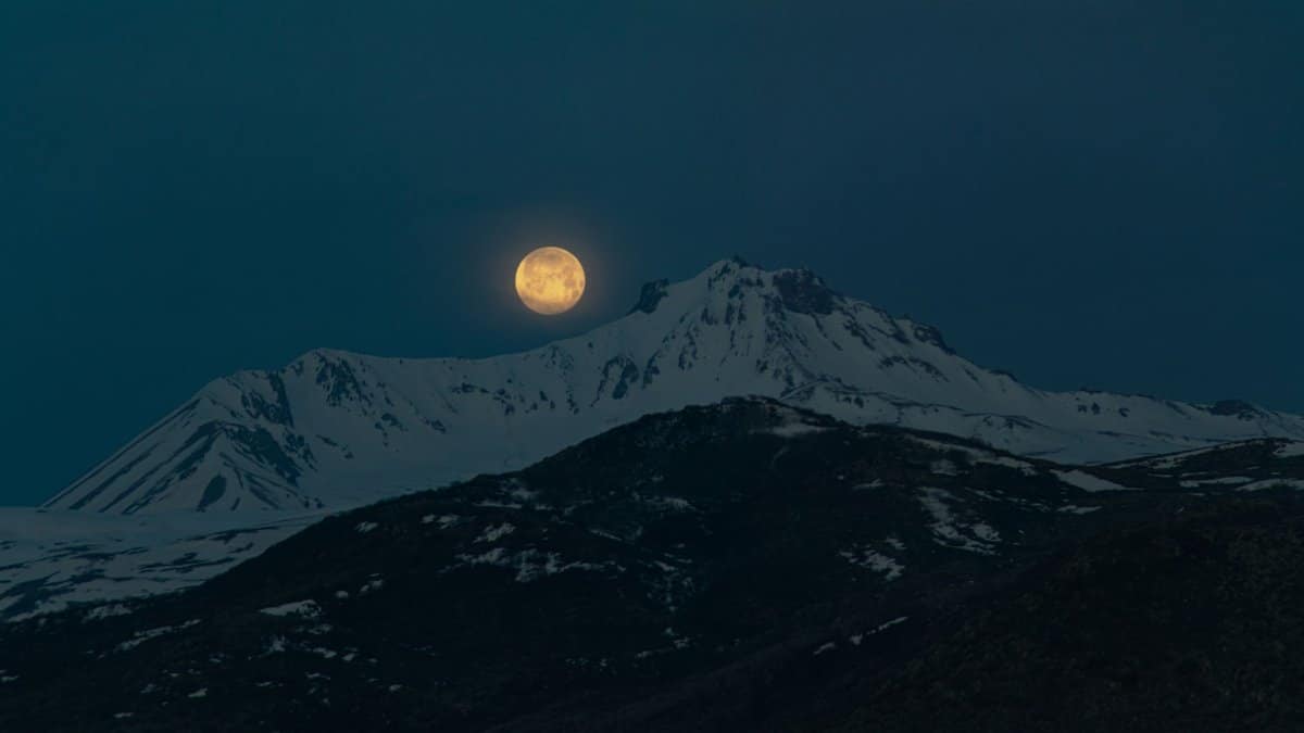 Full moon illuminating the snowy peak of Mount Erciyes in Turkey during a clear night.