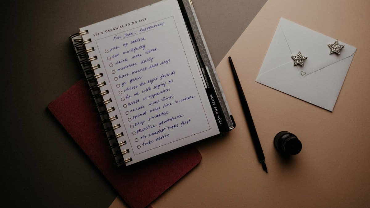 A notebook with new year resolutions and a pen on the desk for organized planning.
