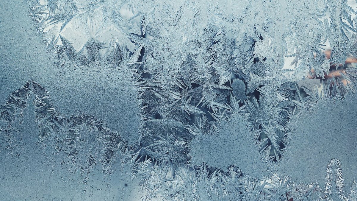 Close-up of intricate frost patterns on a cold winter glass panel.