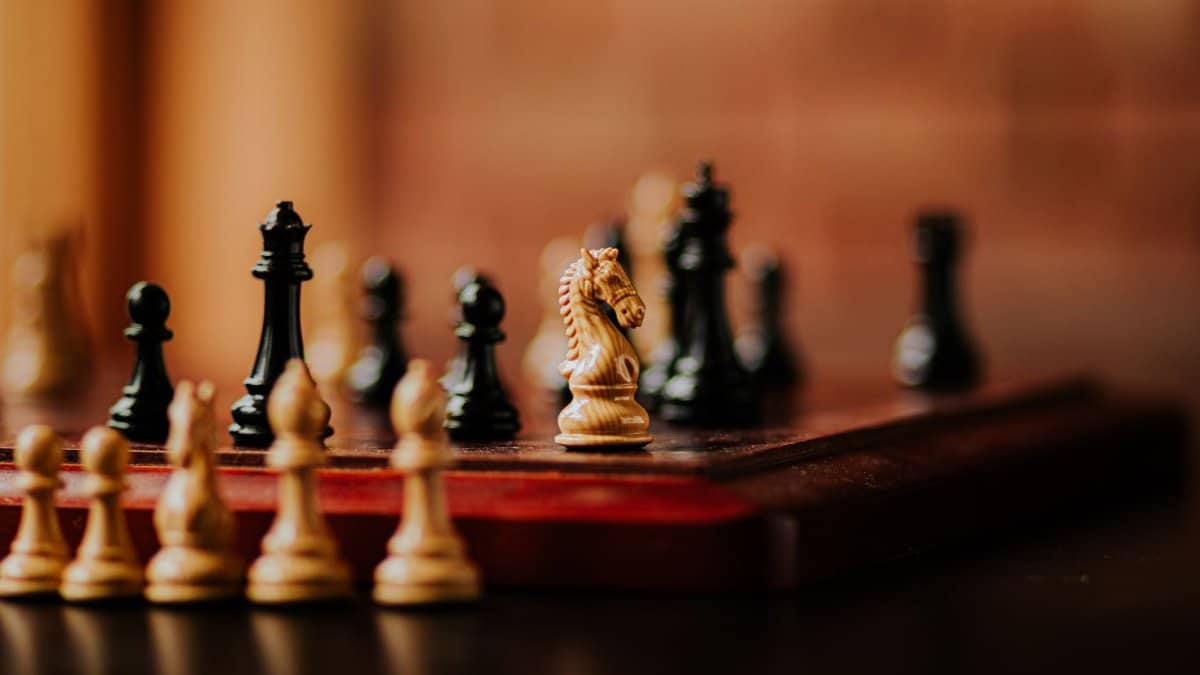 Close-up view of chess pieces on a wooden board. Focused on knight piece, perfect for strategy concepts.