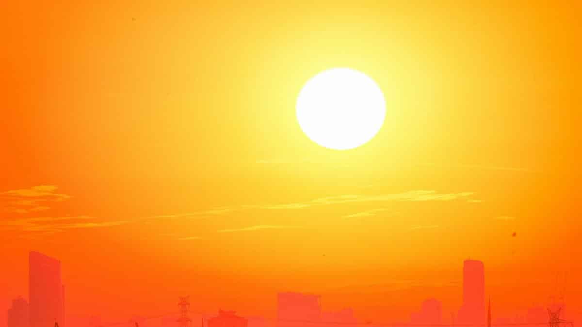 A city skyline silhouetted against a vivid, orange sunset sky.