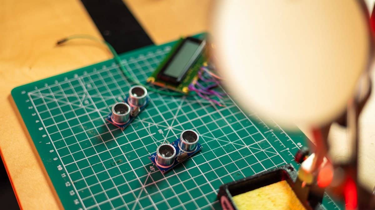 Close-up of a PCB with sensors and tools, highlighting electronics engineering setup.