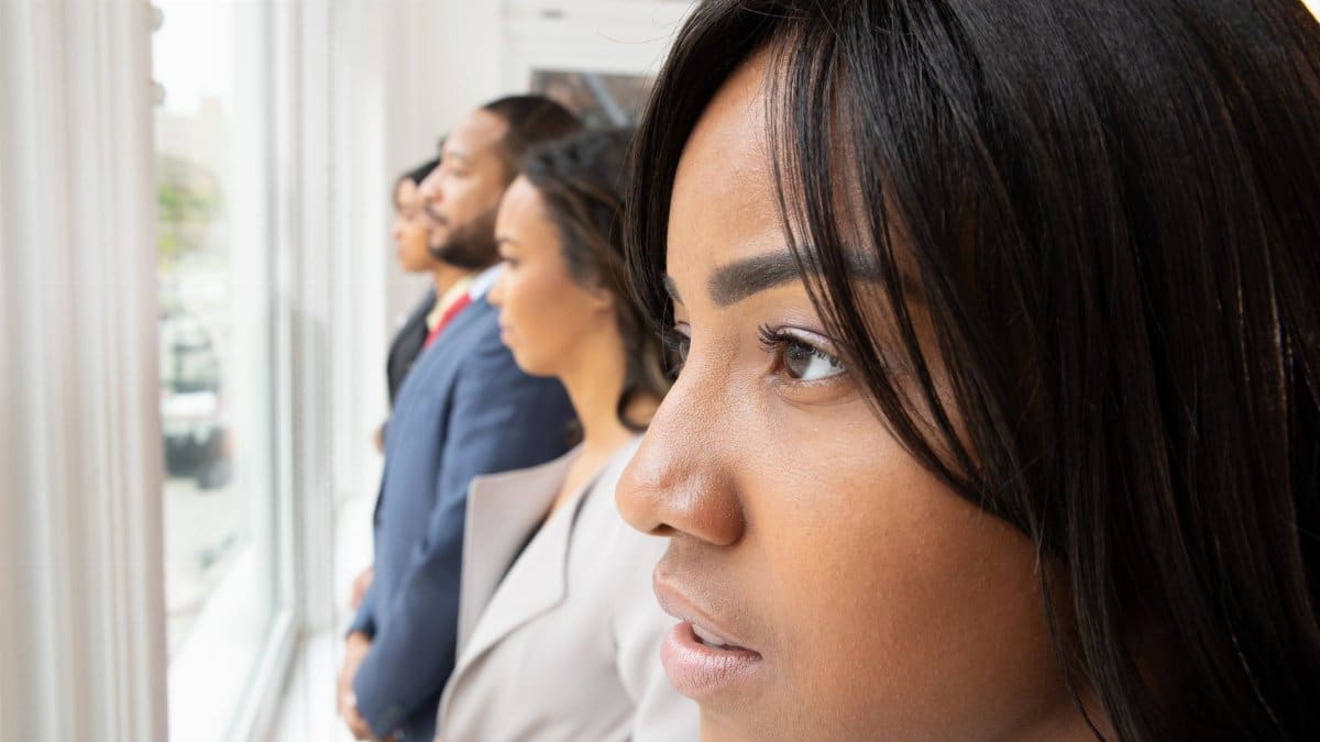 Focused professionals stand by a window, looking out with determination. Teamwork in a modern office.