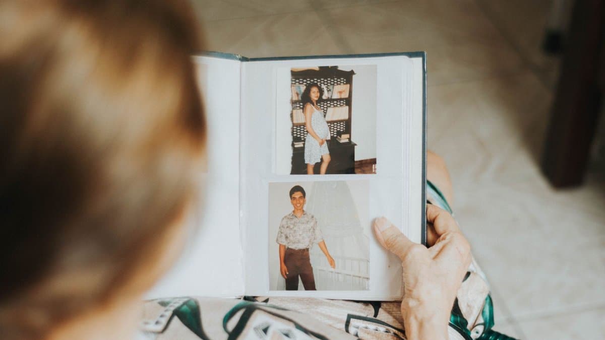 A senior woman reminisces while looking at a photo album indoors.
