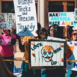 Protesters rally on Wheeling streets holding political signs and banners in a vibrant demonstration.