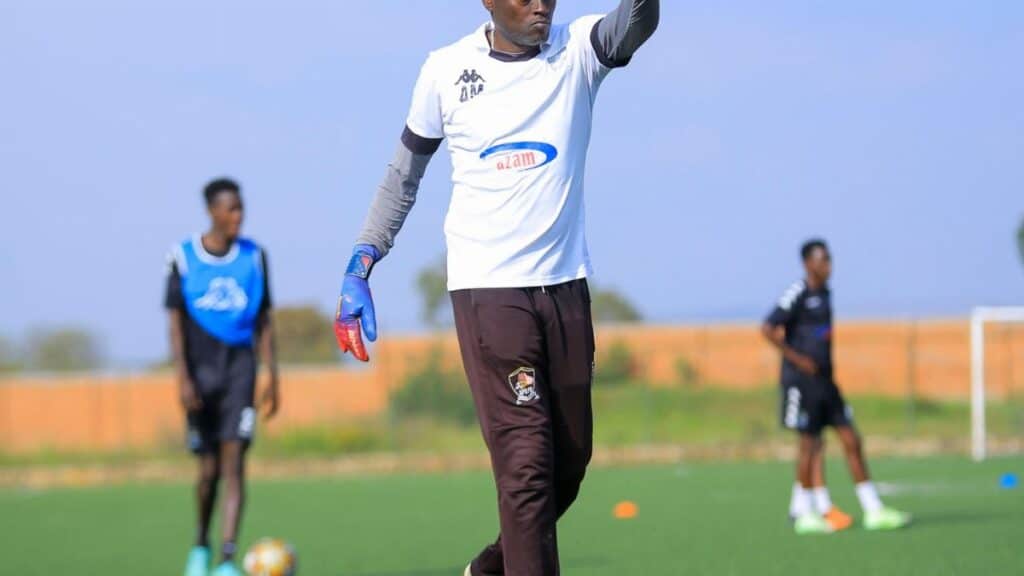 Goalkeeper throwing soccer ball during outdoor team training session.