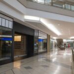 Spacious and contemporary mall interior with closed stores and escalator.