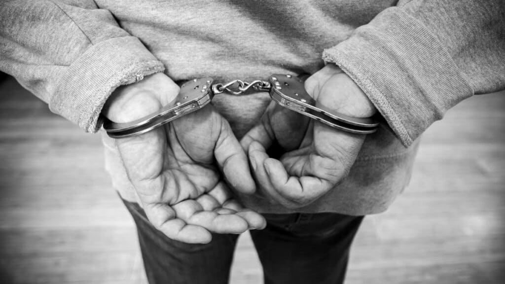 Rear view of a man in handcuffs, captured in monochrome.