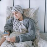 Woman undergoing cancer treatment at home, using a smartphone for support.