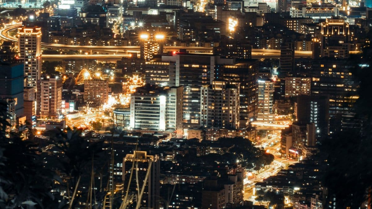 A vibrant city skyline at night with illuminated skyscrapers and bustling streets captured from above.