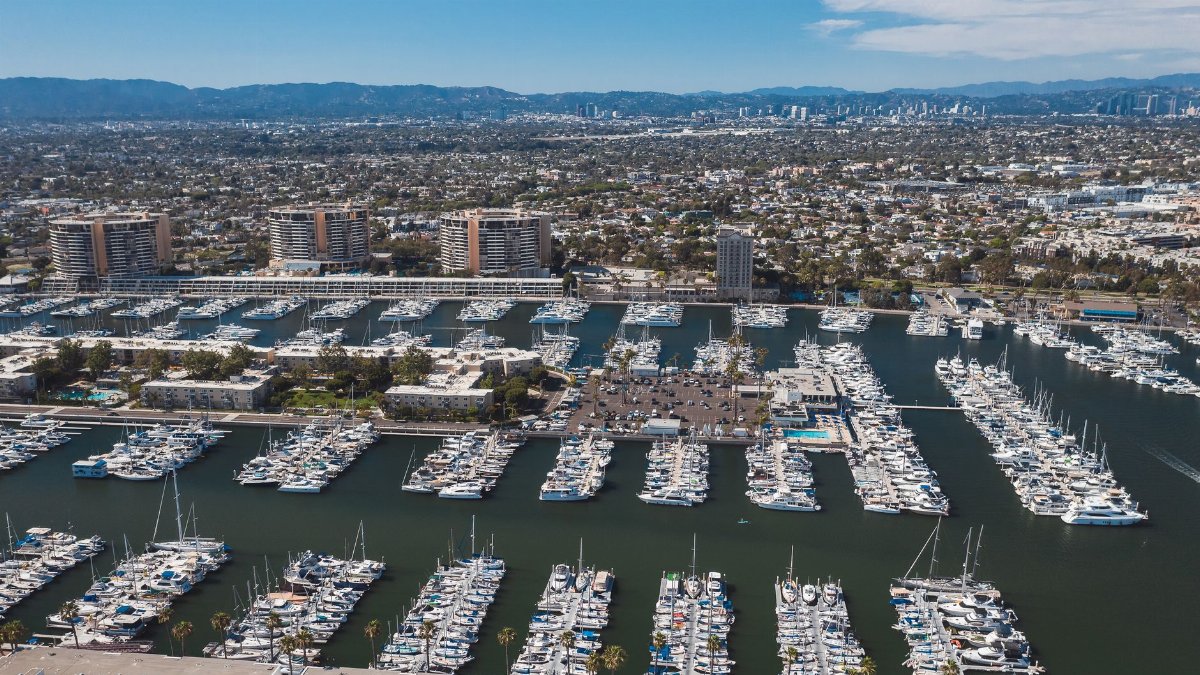 Explore the bustling Marina del Rey Harbor with yachts and cityscape in the background.