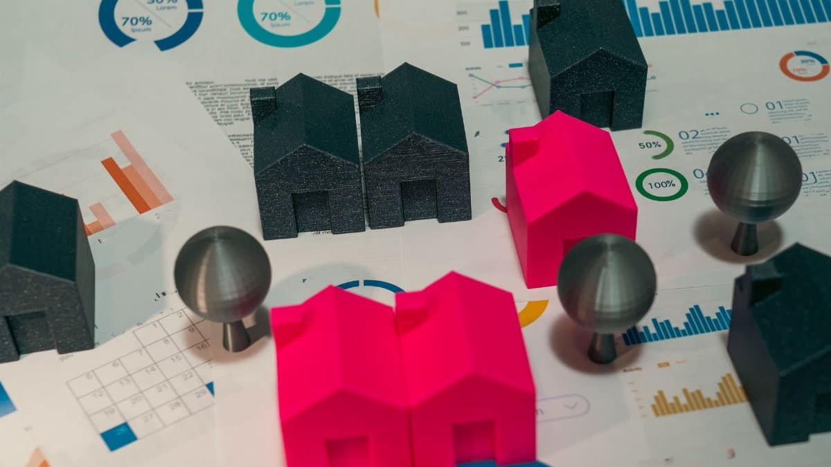 Abstract representation of real estate market analysis with model houses and charts.
