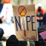 Participants hold anti-monarchy signs at a protest in Baltimore, USA, expressing political sentiments.