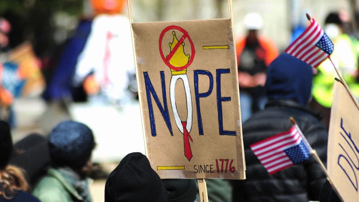 Participants hold anti-monarchy signs at a protest in Baltimore, USA, expressing political sentiments.