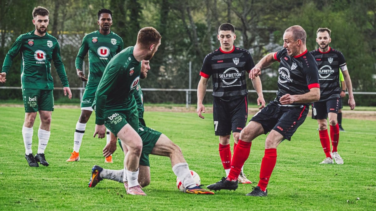 Dynamic football scene with players in action on a green pitch in France.