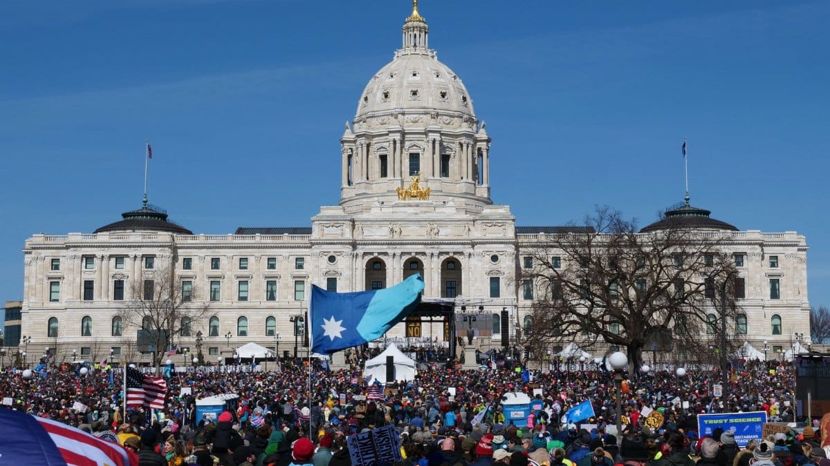 Large crowd protesting at the Minnesota State Capitol in Saint Paul during spring day.