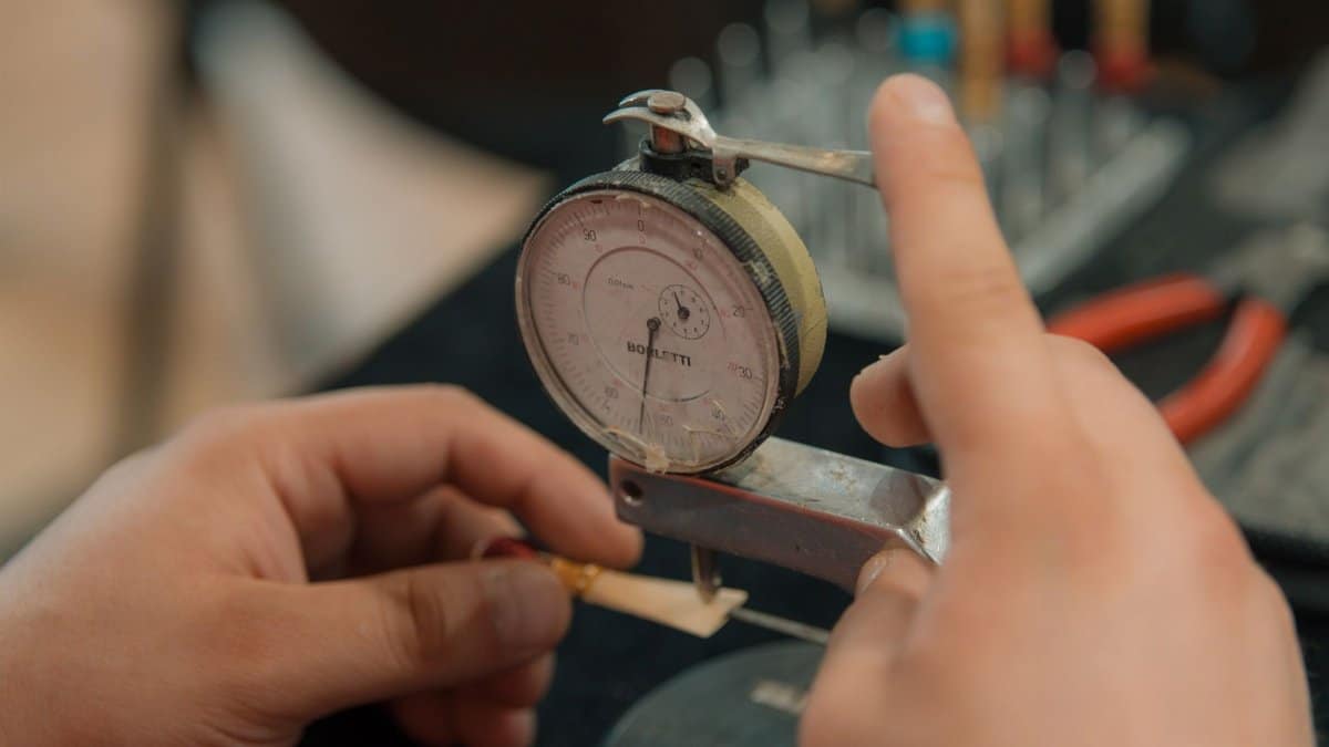 Hands measuring with an analog dial indicator for precision work.