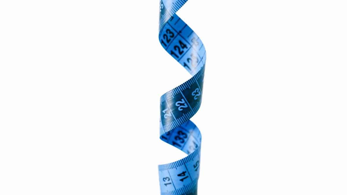 A spiraled blue measuring tape isolated against a white backdrop, symbolizing measurement and precision.