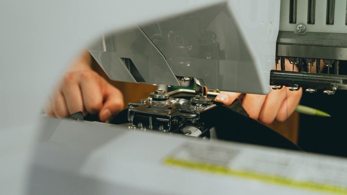 Detailed view of hands working on fabric with a sewing machine, capturing precision and craftsmanship.