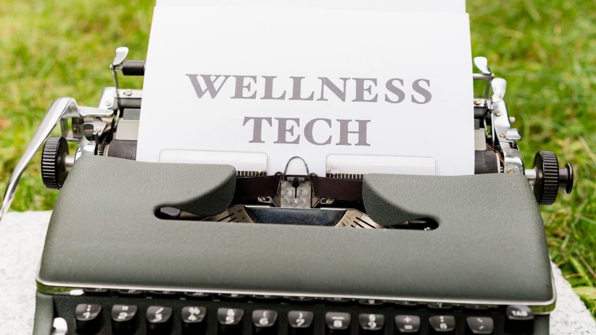 A retro typewriter outdoors displaying a 'Wellness Tech' message on paper.