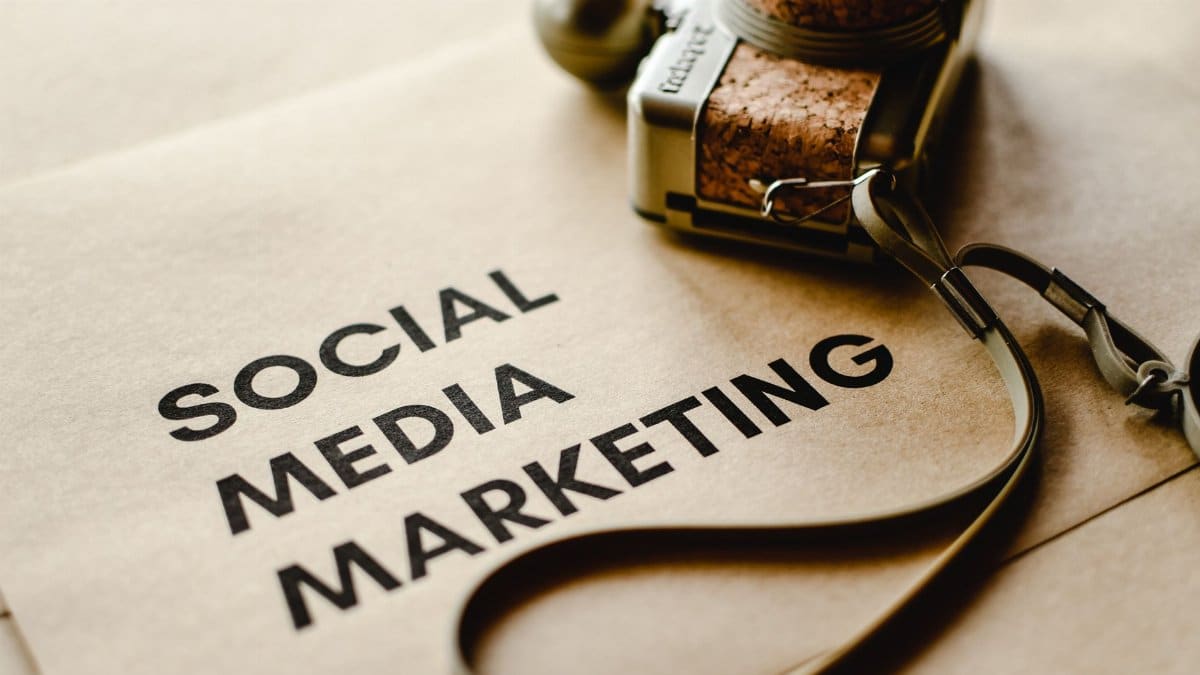 Close-up of a camera placed on brown paper with 'Social Media Marketing' text, emphasizing digital marketing themes.