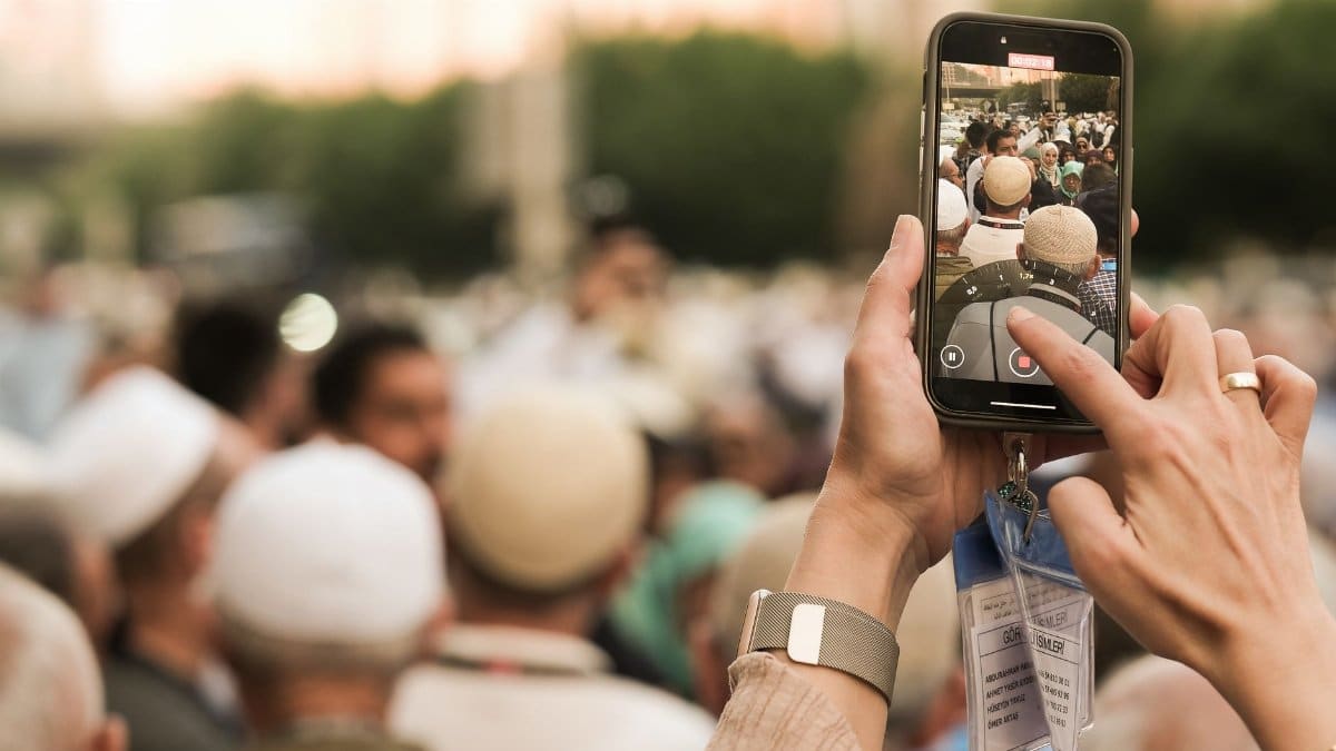 A person recording a vibrant street gathering in Saudi Arabia using a smartphone, capturing cultural moments.