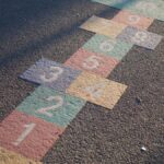 A vibrant hopscotch grid painted on an outdoor playground surface, lit by daylight.