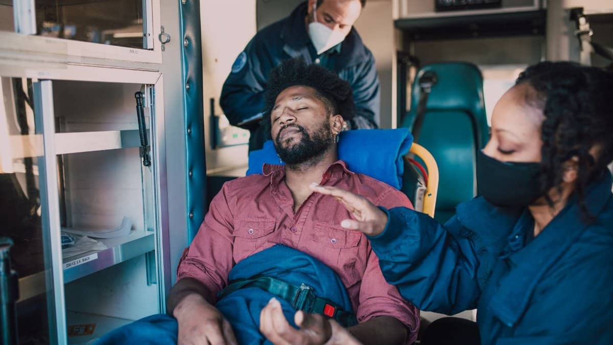 Paramedics provide urgent care to an injured man inside an ambulance.