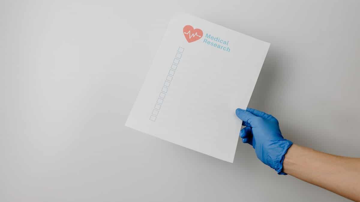 A gloved hand holding a paper titled 'Medical Research' with checkboxes.