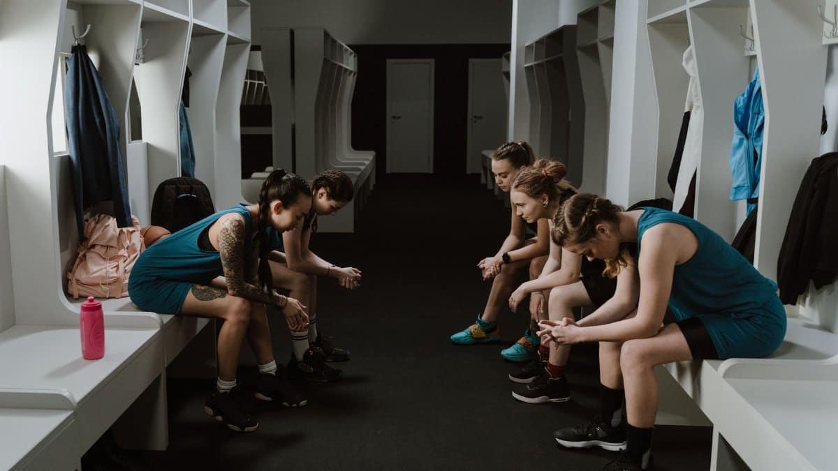 A group of women athletes resting in a locker room wearing sportswear.