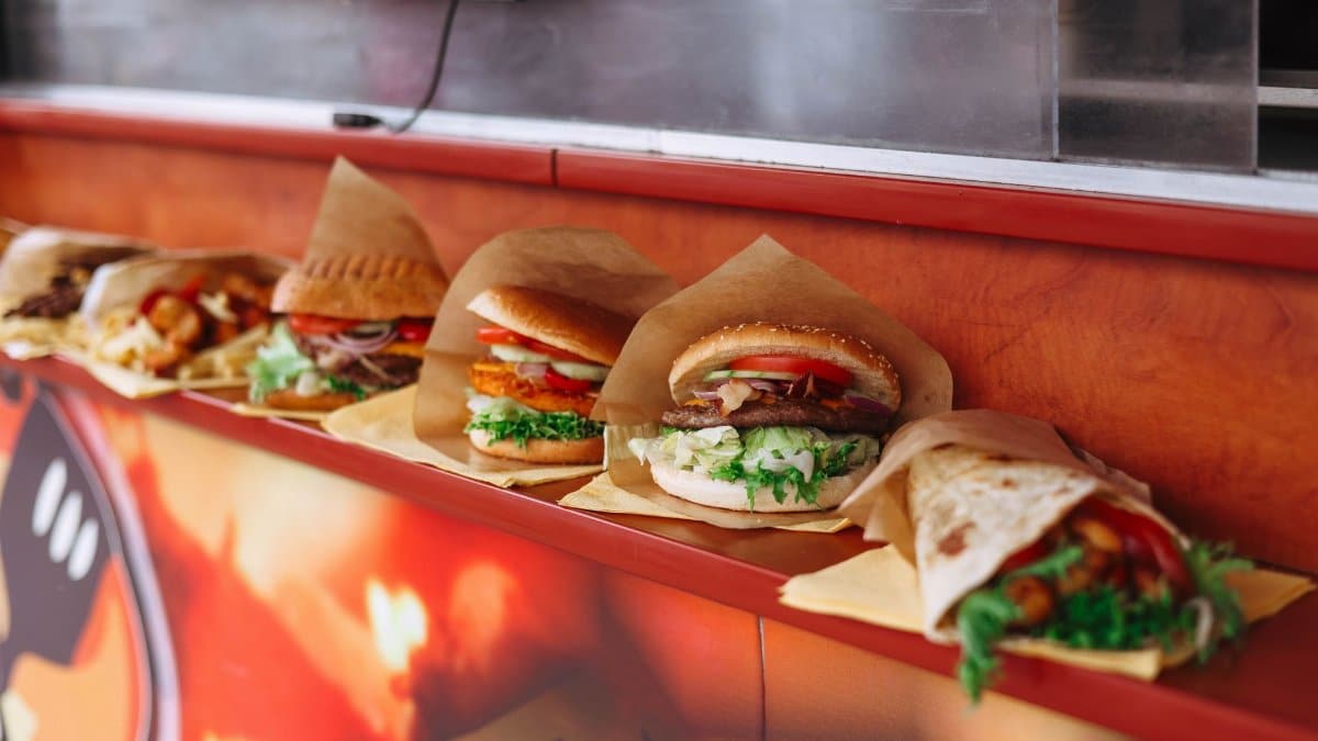 Selection of assorted fast food items like burgers and wraps on a restaurant counter.