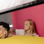 A behind-the-scenes look at a studio photoshoot featuring a model with unique makeup artistry and vibrant background.