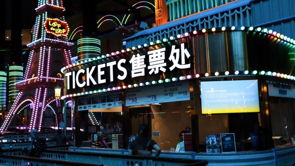 Illuminated ticket booth with vibrant neon lights at night, featuring colorful signage.
