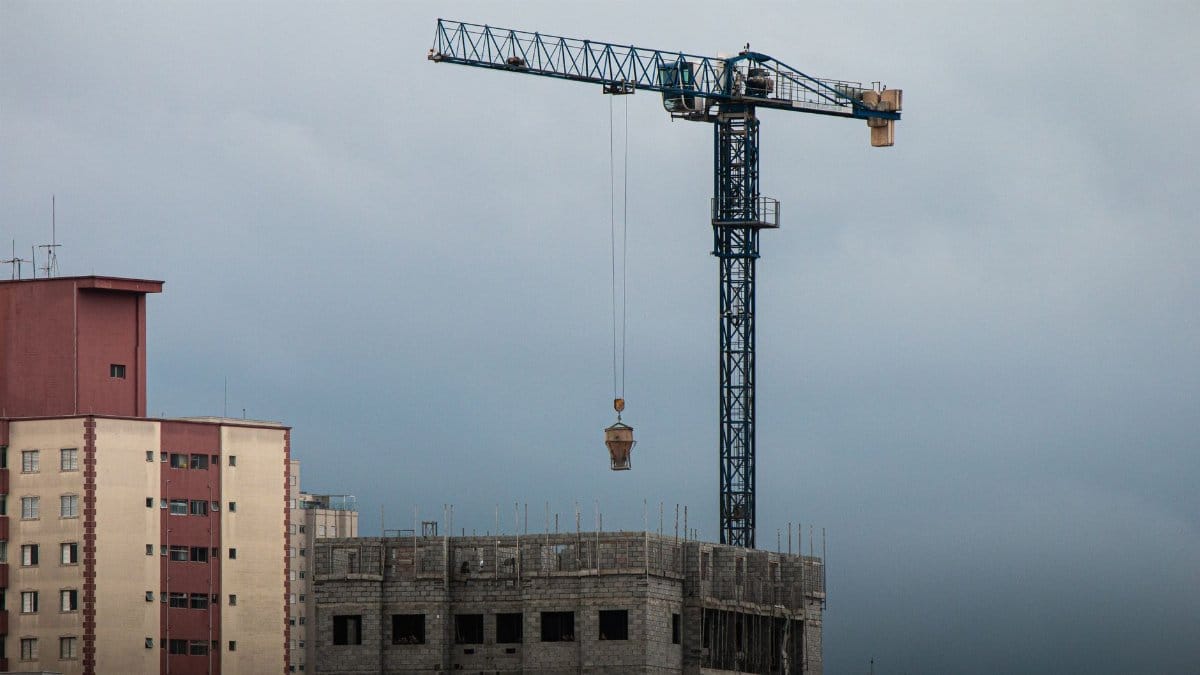 High-rise construction site with a tower crane lifting materials at dusk.