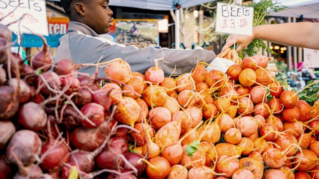 A vivid scene at a farmers market with fresh beets for sale, highlighting local produce and community commerce.