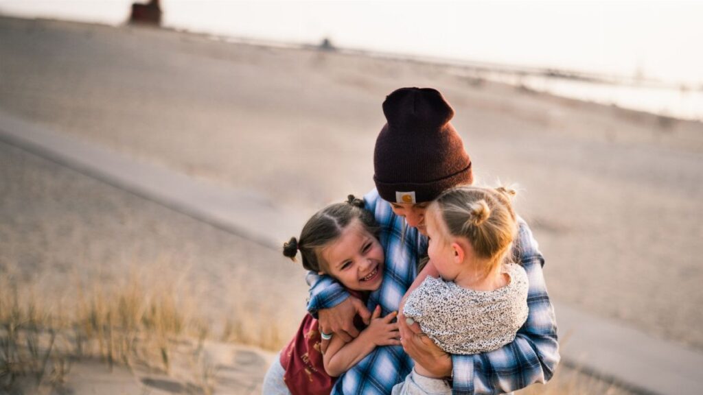 A loving family moment captured on a sunny day at a beach in Holland, MI.