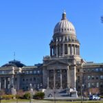 The Idaho State Capitol Building stands majestically under a clear blue sky with surrounding gardens.