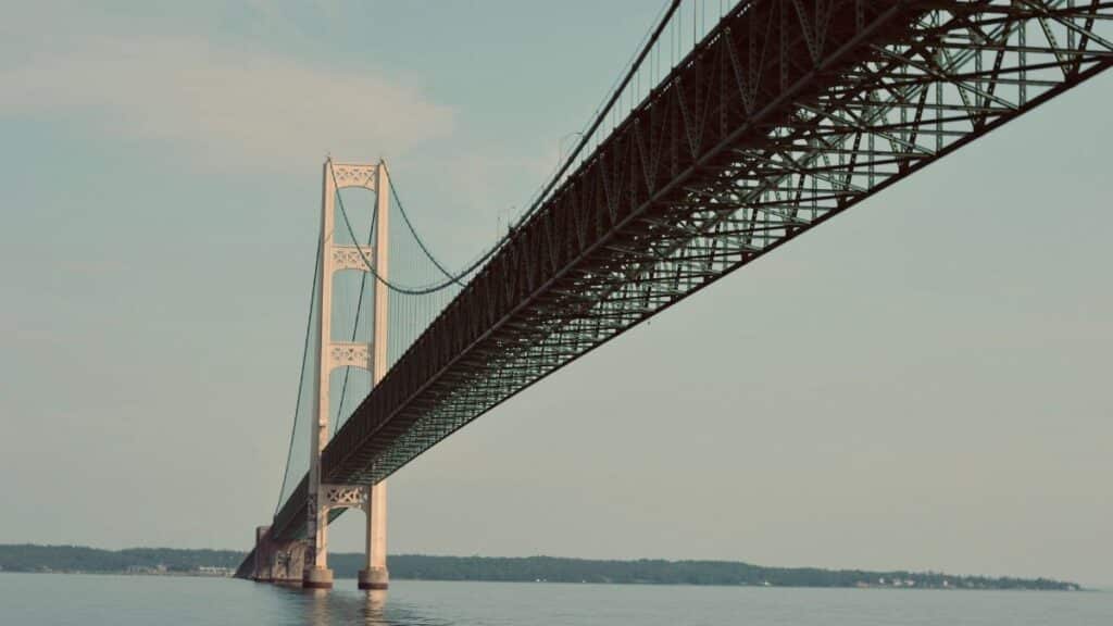 Mackinac Bridge, Michigan, spans over a serene body of water under a clear sky.